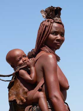 Zamężne kobiety Himba noszą na czubku głowy skurzany czepiec (embrę) oraz wiszącą między piersiami muszelkę - symbol płodności (fot. Namibia Tourism)